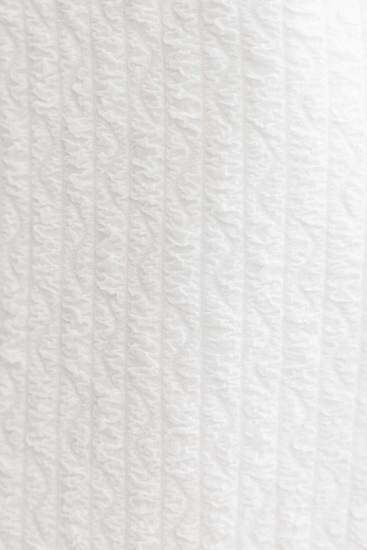 Textured white fabric close-up showing ribbed details, perfect for a stylish maxi dress.