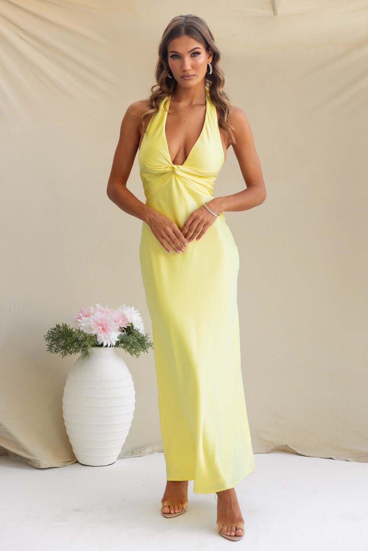Model wearing a yellow tulip maxi dress with a halter neckline and side knot, styled against a neutral background.
