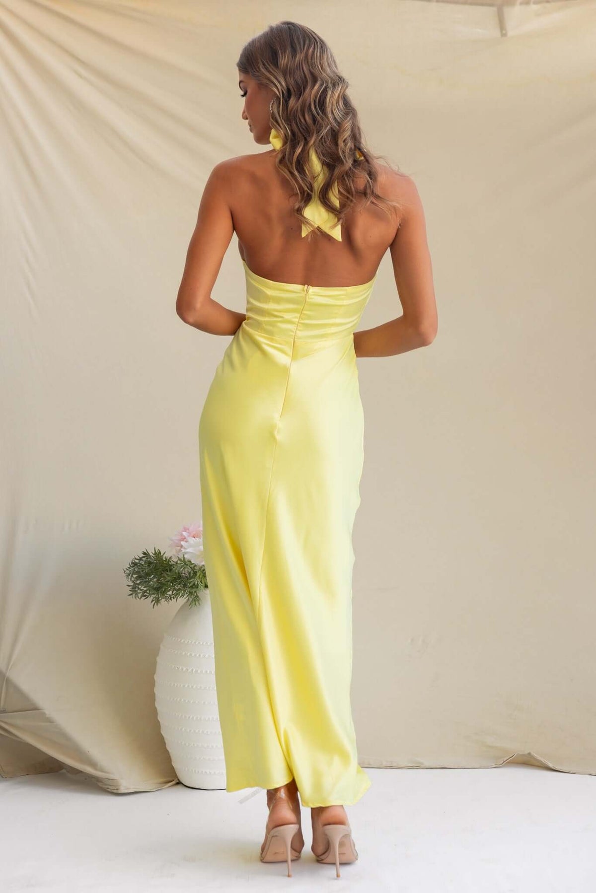 Back view of a model wearing a yellow satin Tulip Maxi Dress with a fitted bodice and a stylish silhouette.