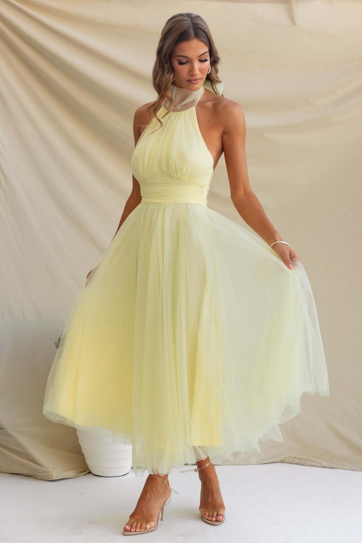 Woman in a yellow Love Lane Maxi Dress with gathered bust detail and adjustable halter neckline, showcasing a tulle skirt.