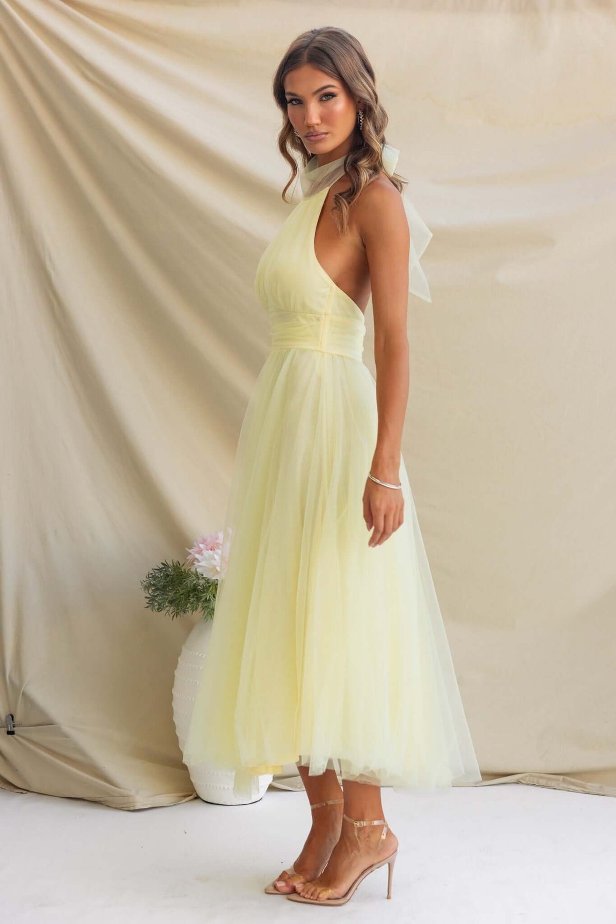 Model wearing Love Lane Maxi Dress with tie halter neckline and gathered bust, in soft yellow tulle fabric.