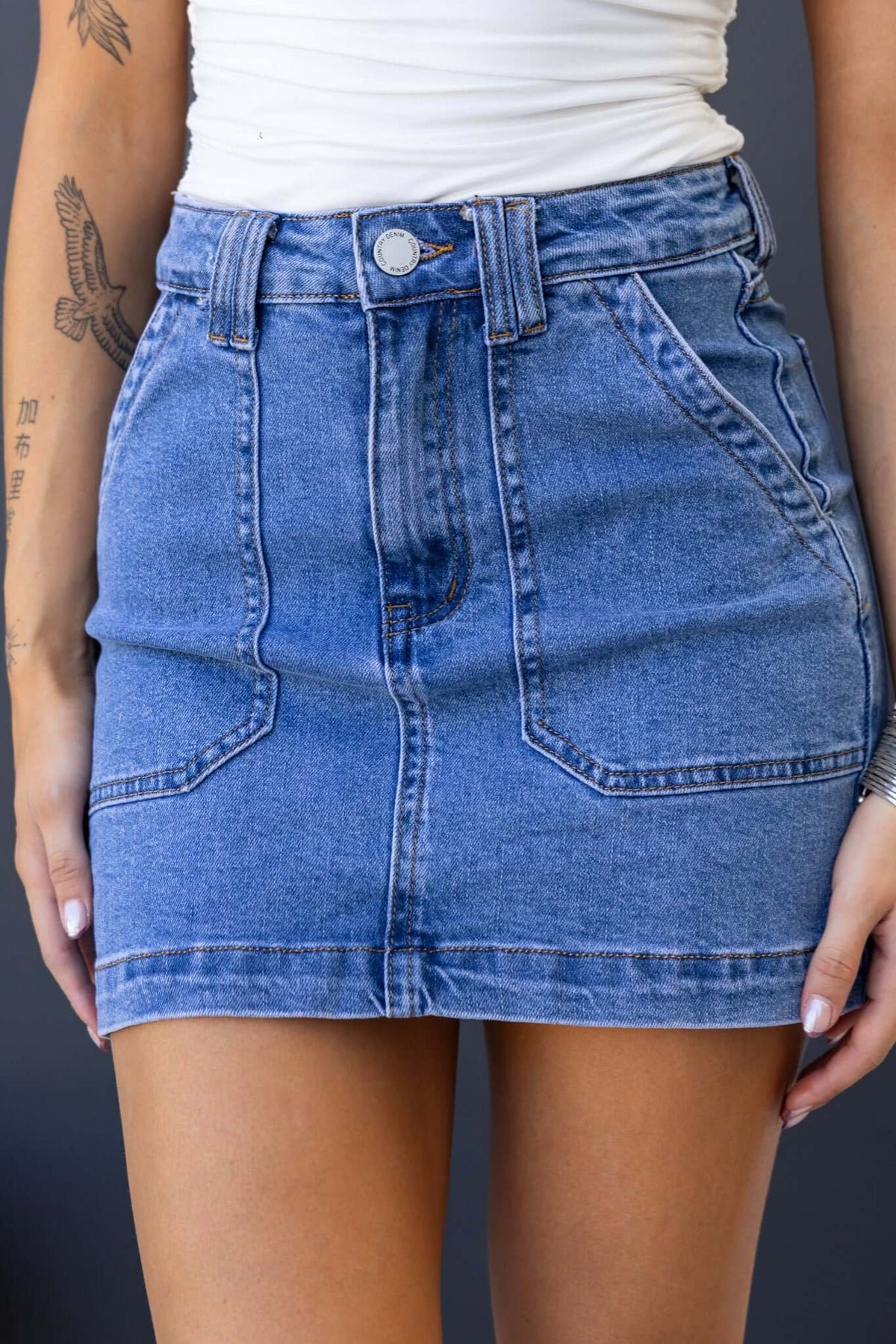Rizzie Denim Skirt featuring mid-high waist, pockets, and stretch material for a stylish, comfortable fit.