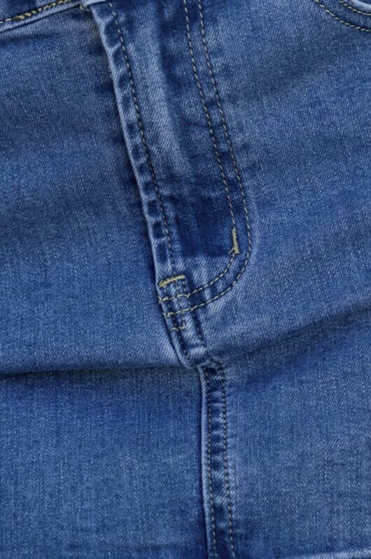 Close-up of Jaya Denim Skirt fabric showing stitching, pocket detail, and dark blue wash.