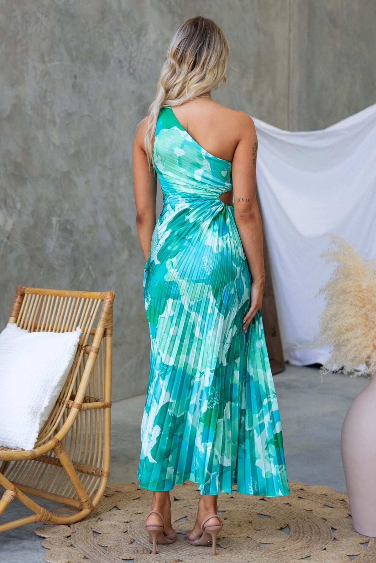 Back view of the Ottile Maxi Dress featuring a one-shoulder design and cut-out waist, styled in a vibrant green print.