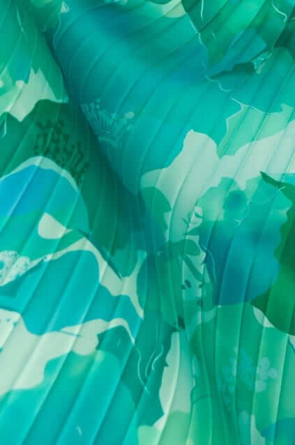 Close-up of accordion pleat fabric in teal and floral print, showcasing texture and vibrant colors for the Ottile Maxi Dress.