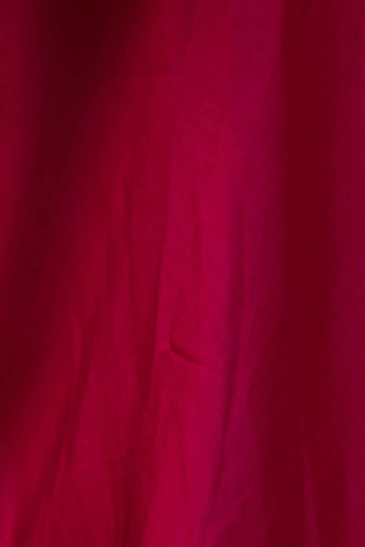 Close-up of rich burgundy fabric, showcasing its texture and vibrant color, ideal for stylish garments.