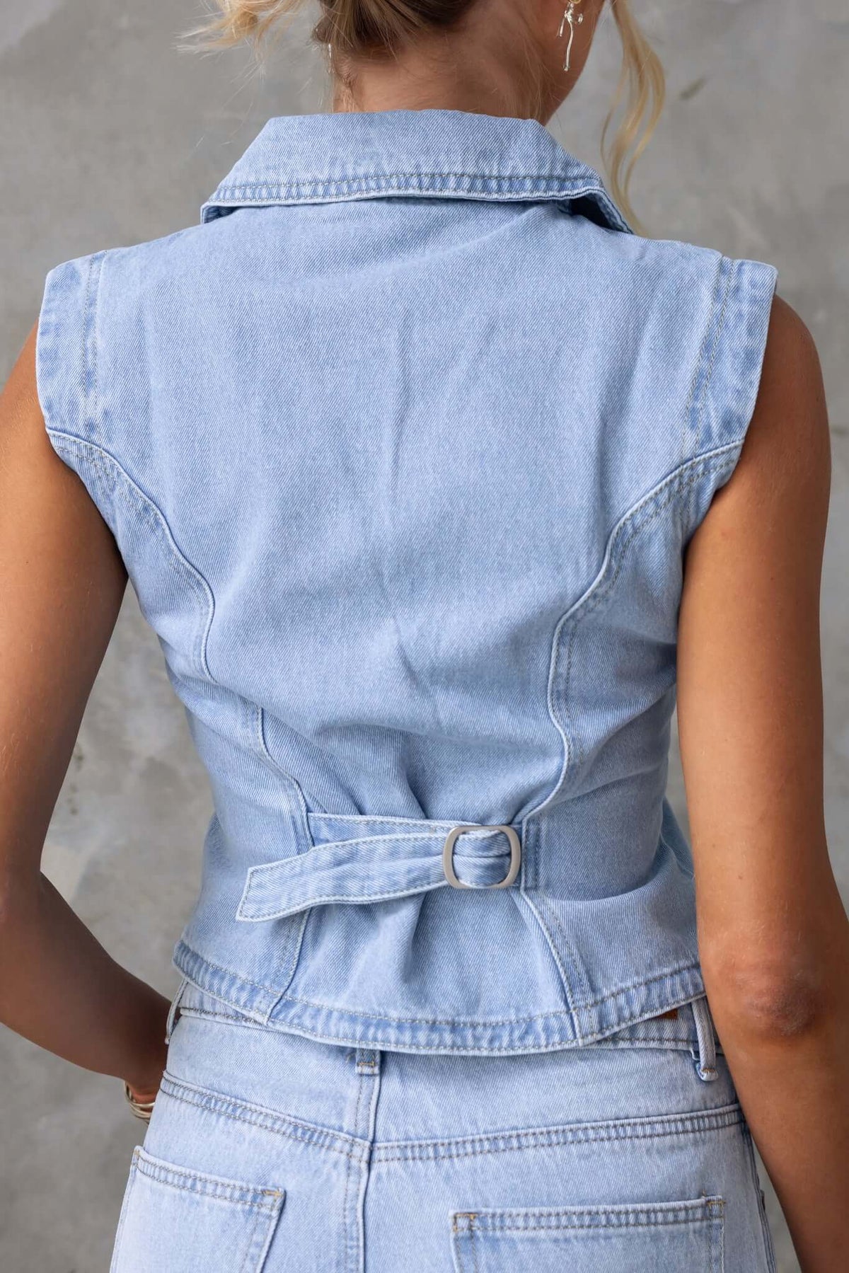 Back view of Billie Denim Top with collar, button-up front, and buckle detail in light blue denim.