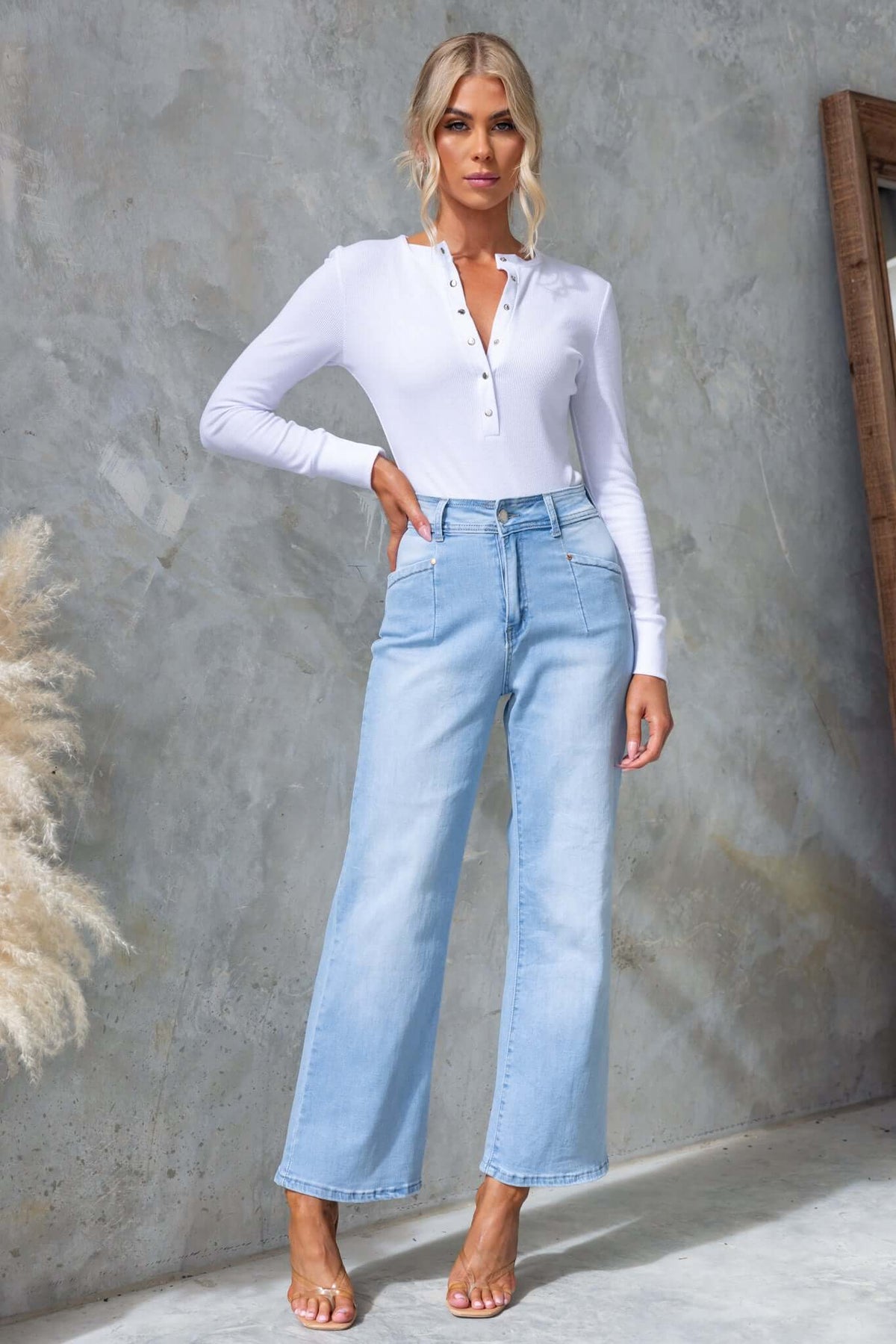 Blanca Jeans in light blue, featuring mid-high waist and wide leg design, styled with a white long sleeve top.