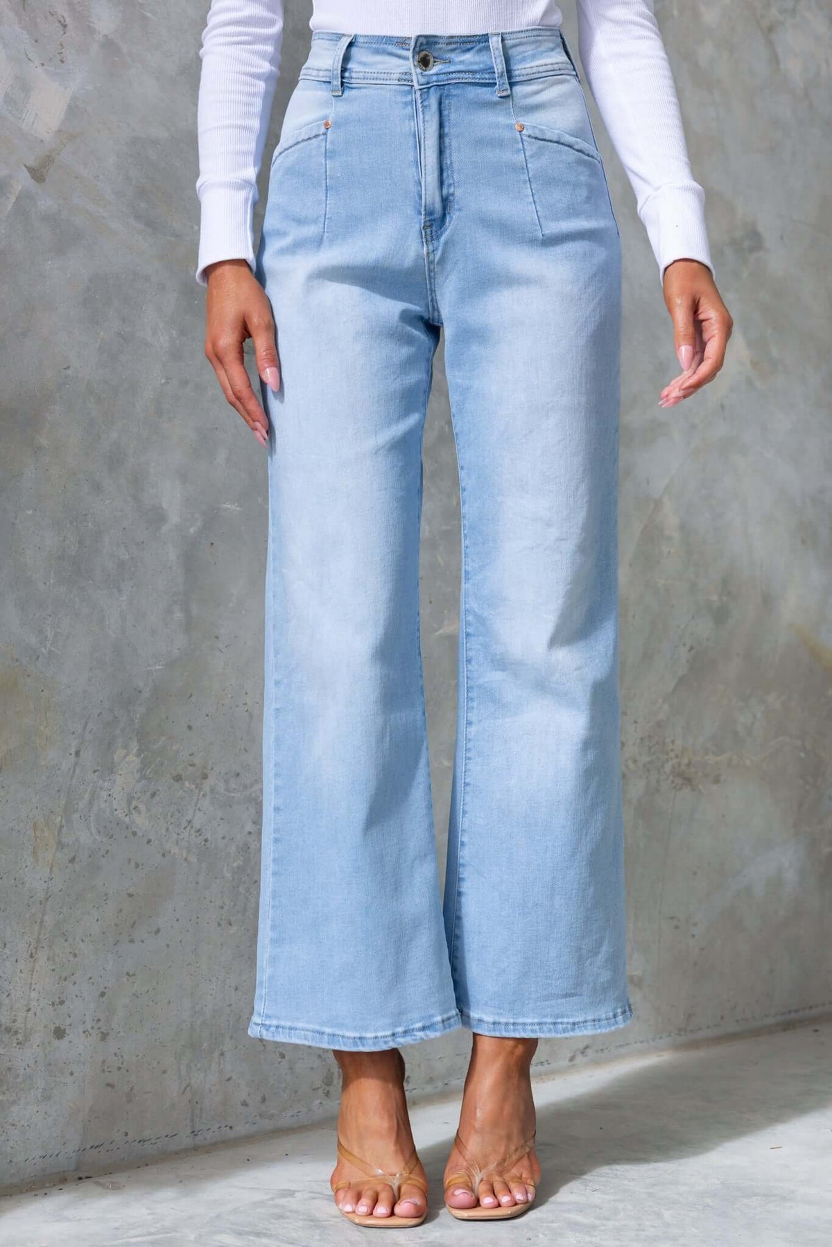 Light blue wide-leg denim jeans with mid-high waist and pockets, modeled by a woman.
