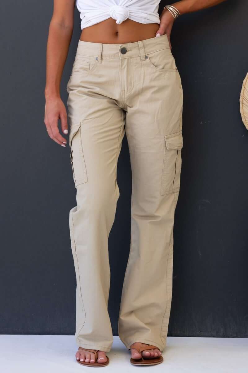 Model wearing Bowie Cargo Pants in beige, featuring a low-mid waist, wide legs, and multiple pockets.
