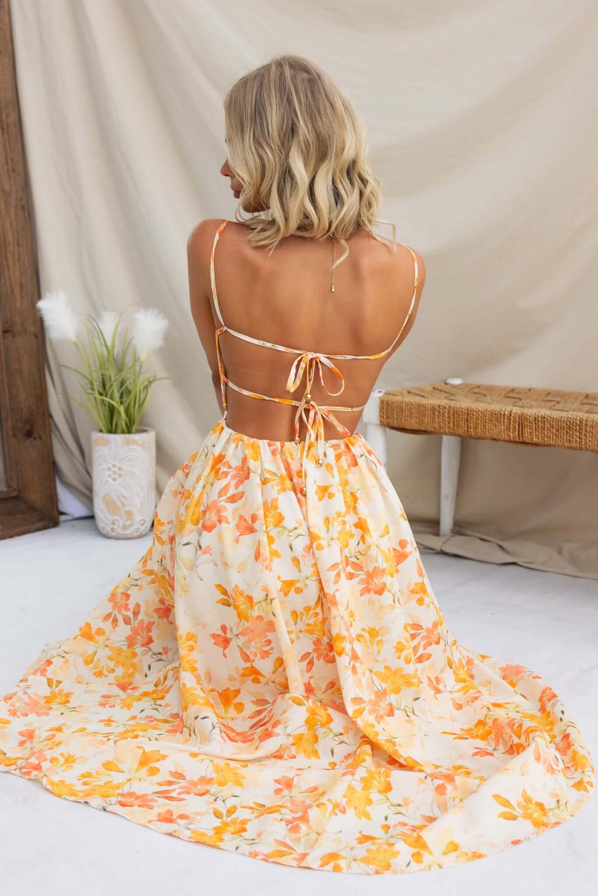Back view of Burkes Midi Dress featuring adjustable tie straps and a floral design in orange and yellow.