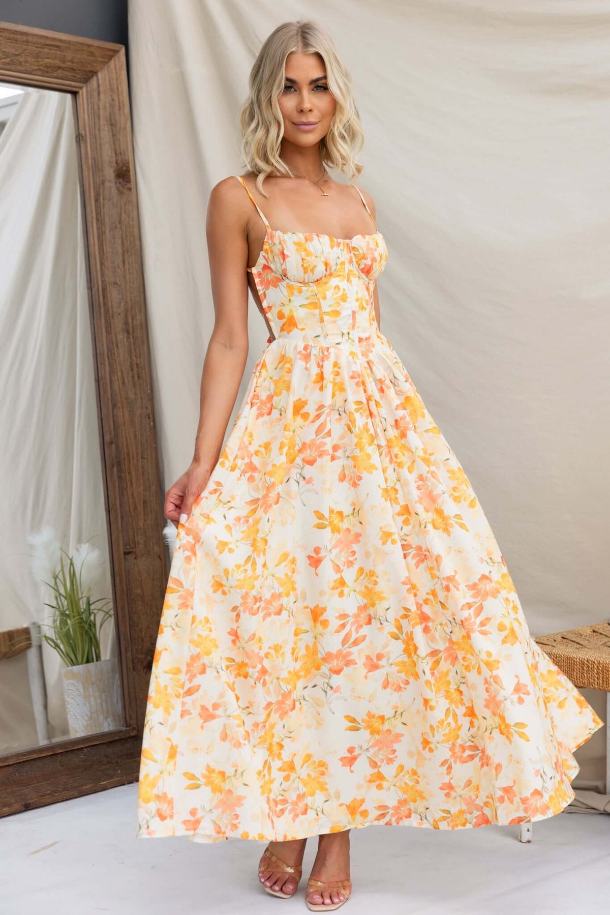 Burkes Midi Dress featuring adjustable tie straps and floral print in orange and yellow with a flowing silhouette.