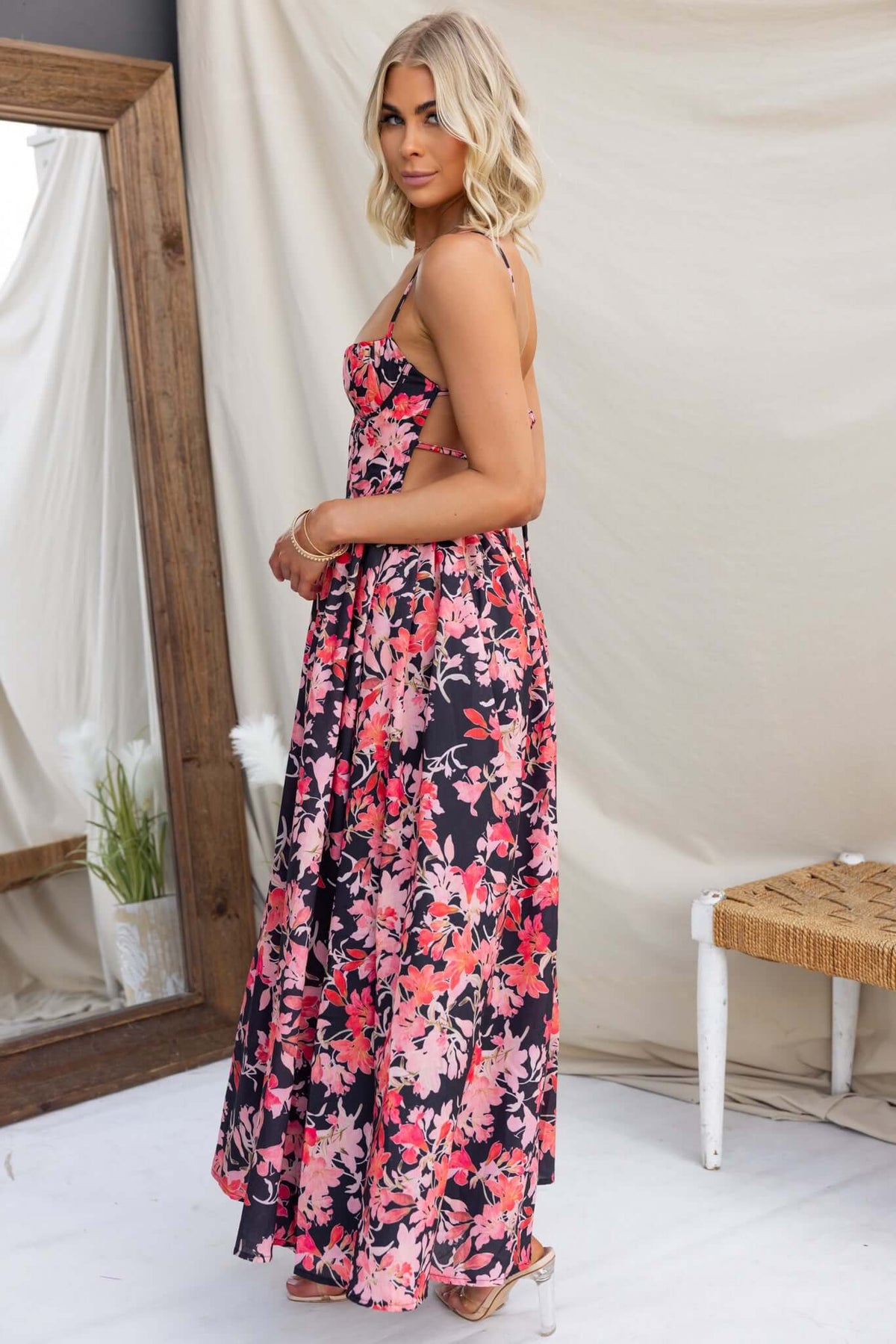 Model wearing Burkes Midi Dress featuring floral print, adjustable straps, and a flowing silhouette from the back.