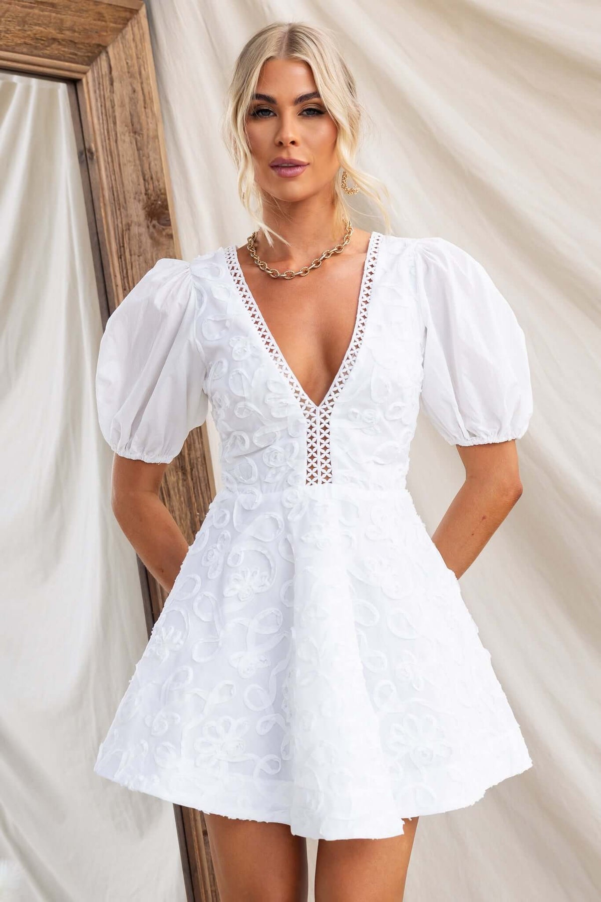 Casen Dress in white with V-neckline, puff sleeves, and lace trim details.