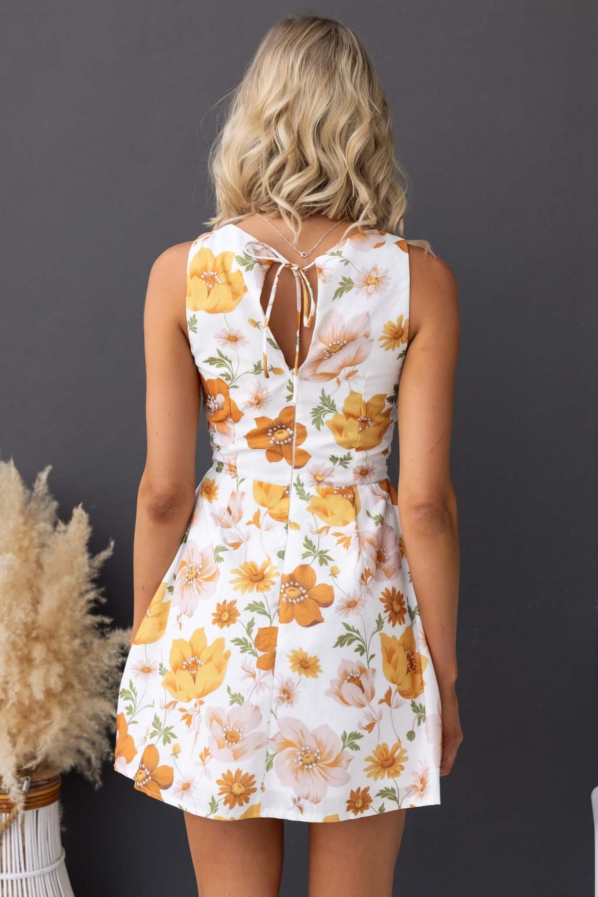 Back view of Clover Dress with floral print, tie detail, and invisible zip, perfect for summer outings.