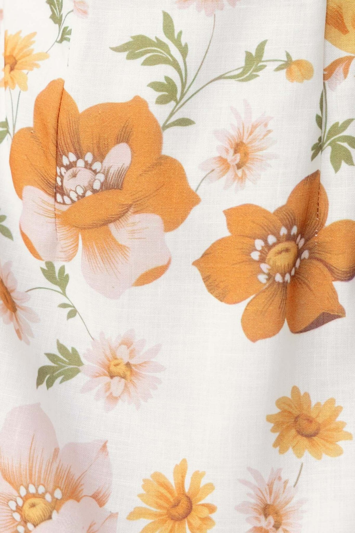 Close-up of floral pattern with orange flowers on a light background, featured on the Clover Dress.