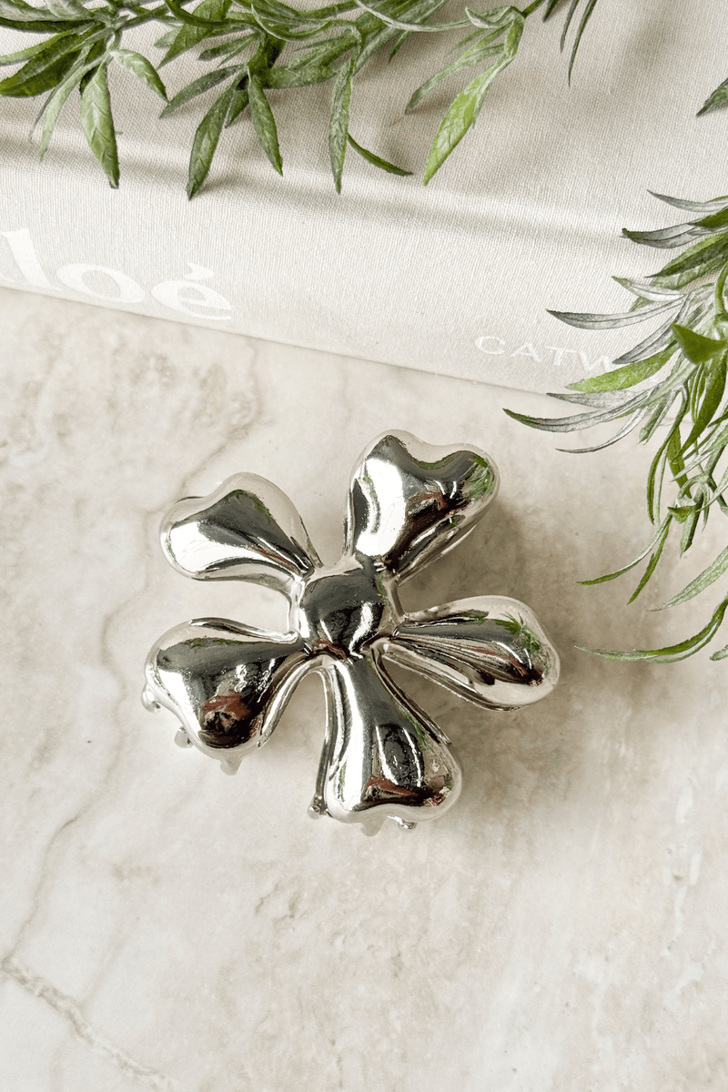 Daisy claw clip with a metallic finish, measuring 7.5cm, beautifully styled on a marble surface.
