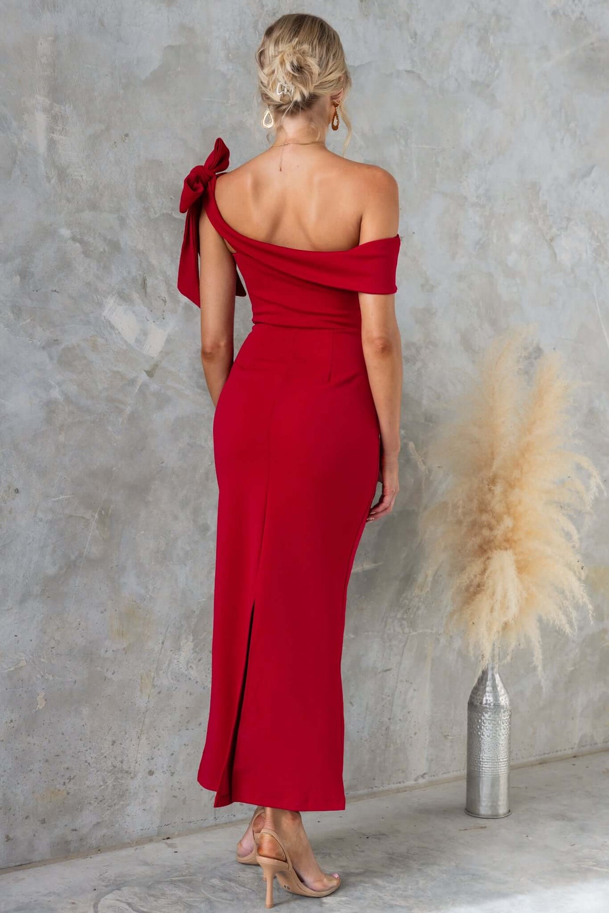 Back view of a woman in a red Devon Midi Dress featuring an asymmetric neckline and side split, styled elegantly.