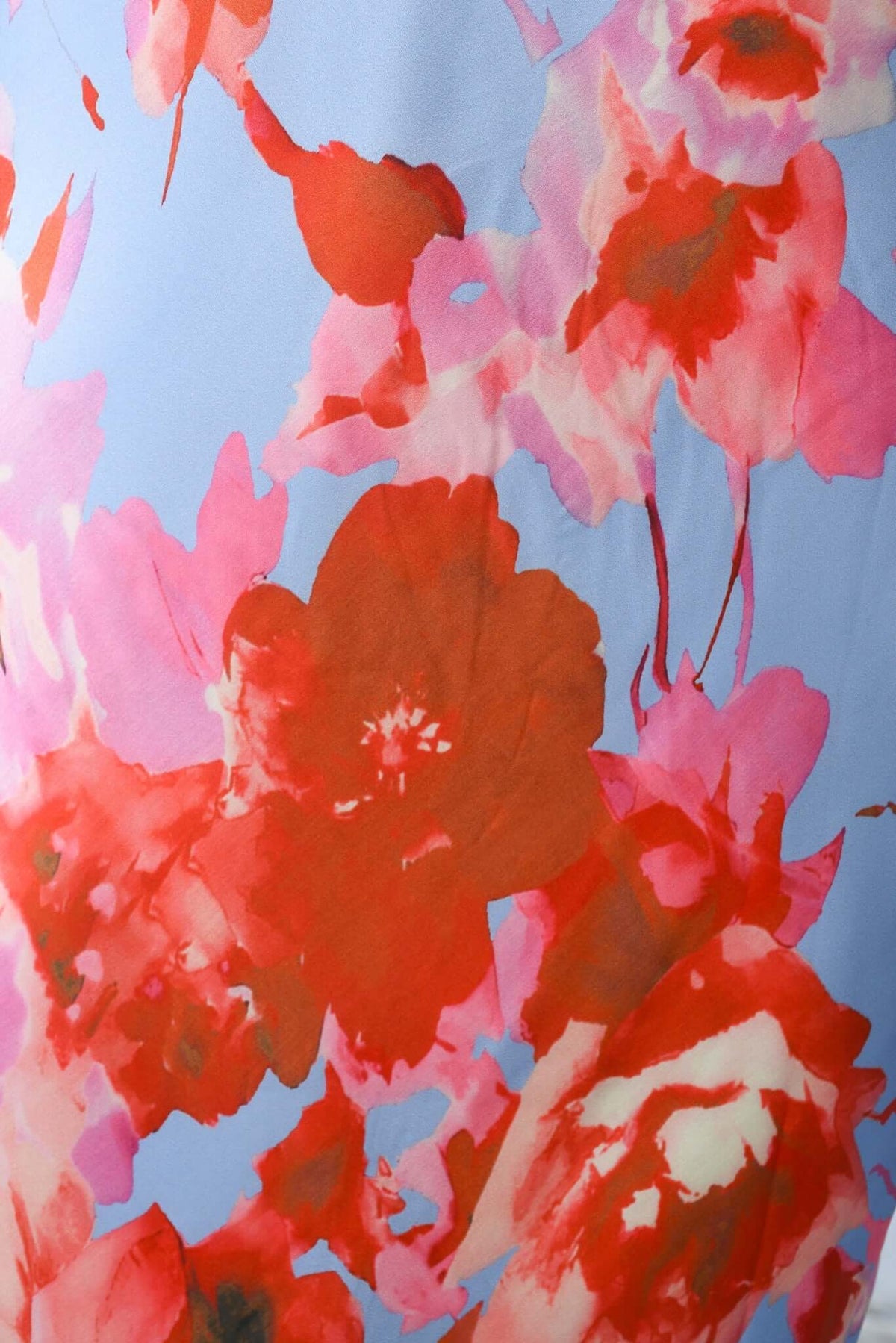 Floral pattern detail on the Forbidden Love Maxi Dress featuring vibrant red and pink blossoms against a light blue background.
