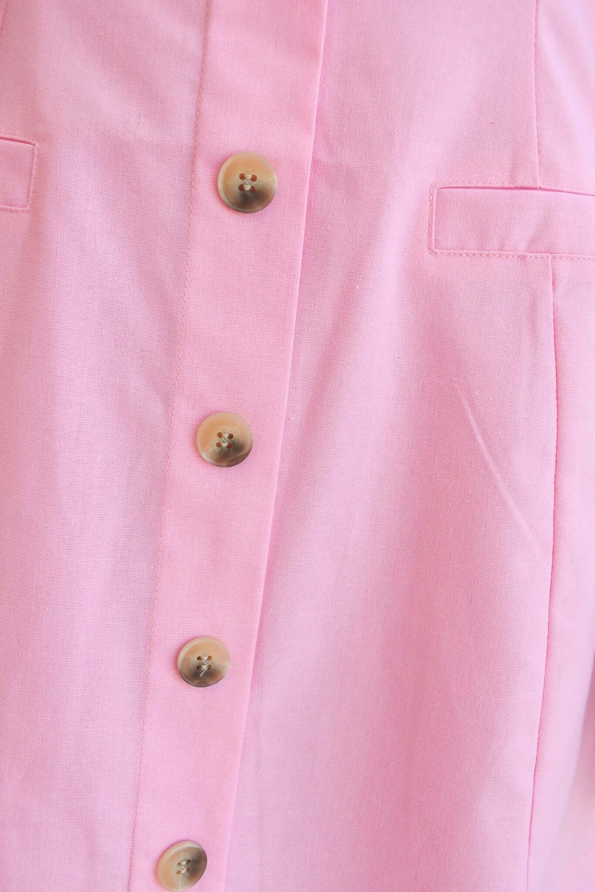 Close-up of a pink dress featuring faux buttons and pockets, ideal for stylish women's casual wear.