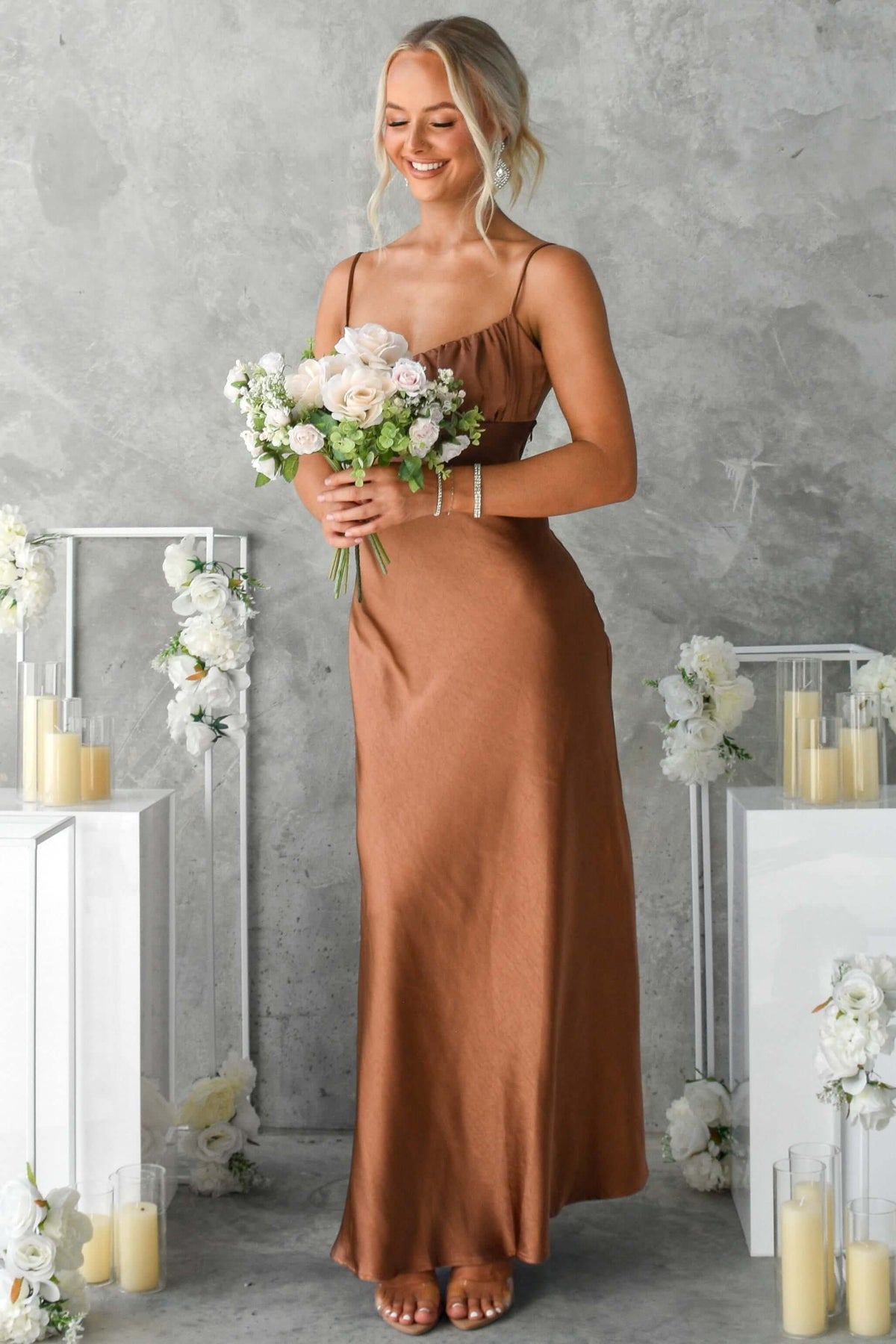 Model wearing Maeya Maxi Dress in brown with flowers, showcasing adjustable straps and elegant satin design.