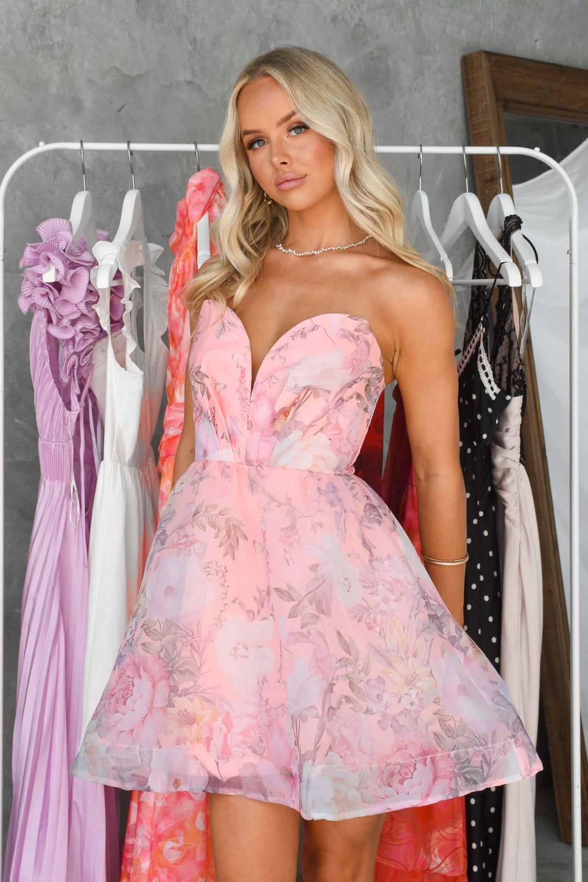 Model wearing the Stella Dress, a pink, strapless floral dress with an elegant silhouette, showcasing style and comfort.