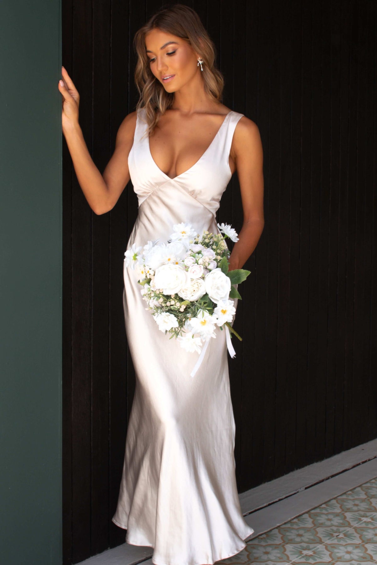 Elegant Darina Maxi Dress with V-neckline, satin material, worn by model holding a bouquet.