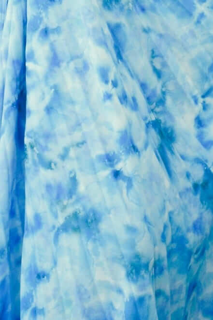 Close-up of soft blue tie-dye fabric showcasing accordion pleats, ideal for a stylish Tejano maxi dress.