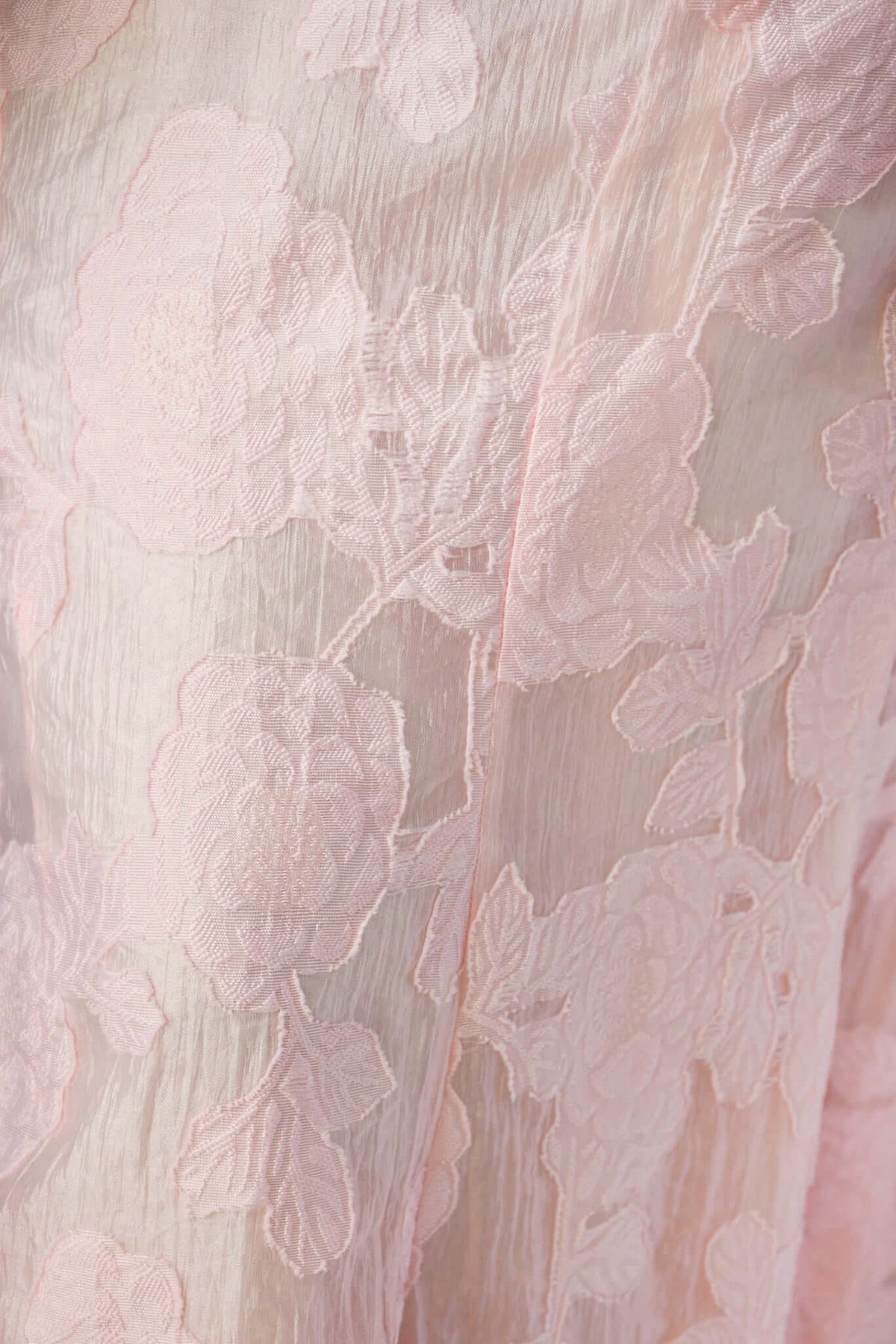 Close-up of delicate pink floral lace texture, showcasing intricate embroidery details on soft fabric.
