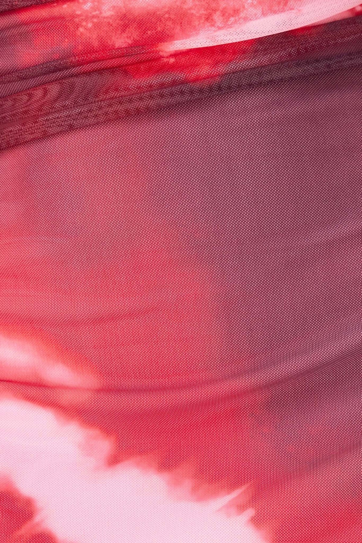 Close-up of the stretchy mesh material in a red tie-dye pattern for an eccentric maxi dress.