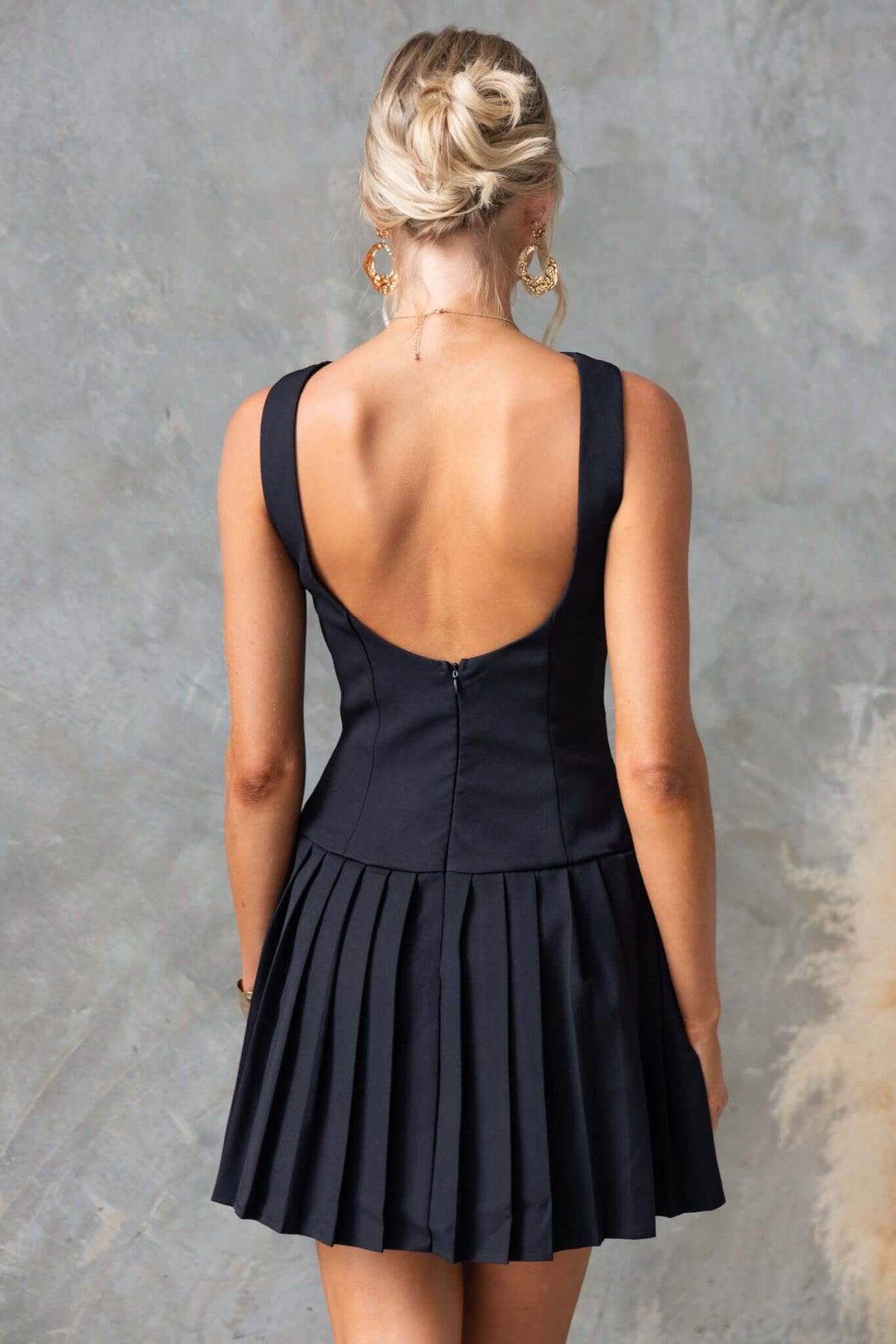 Back view of the Empoli Dress featuring a high neckline, pleated skirt, and invisible zip closure.