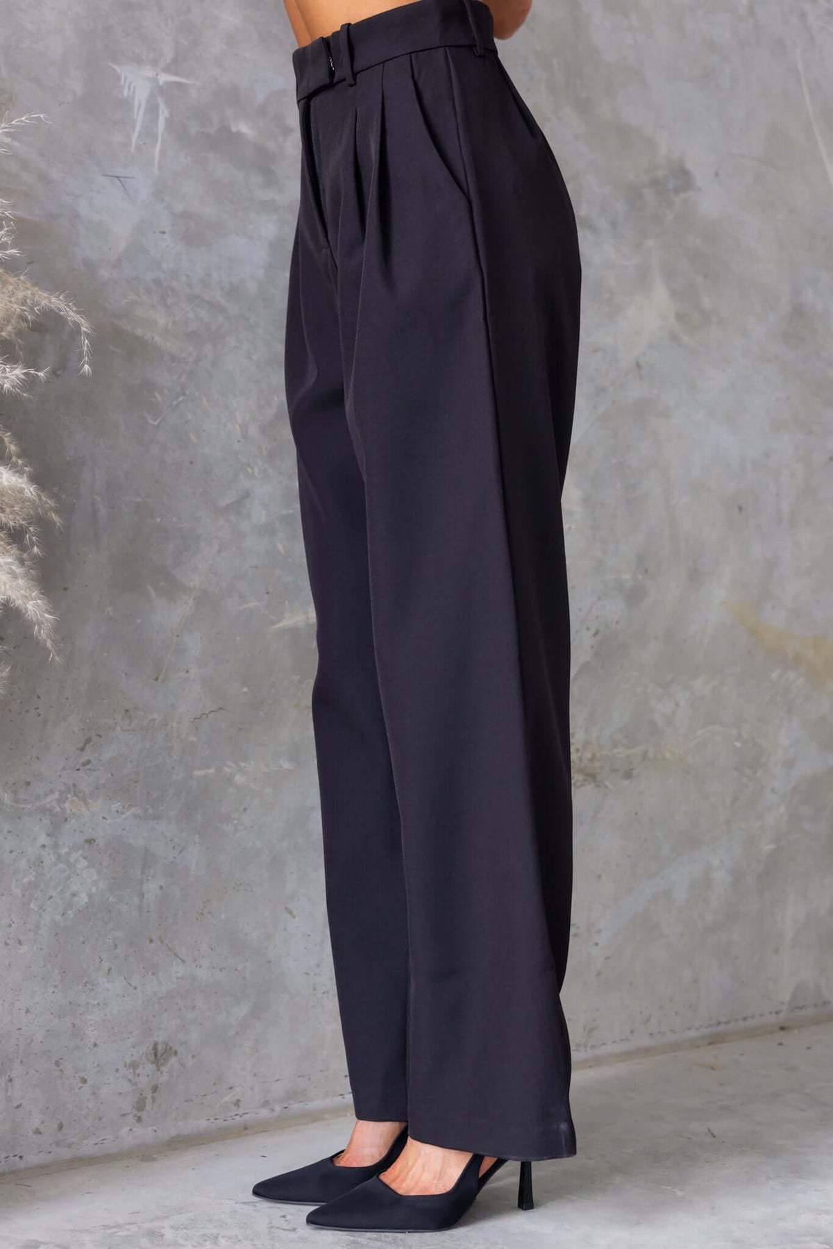 Gette Pants in black, featuring a mid-high waist fit, pockets, and non-stretch polyester fabric.