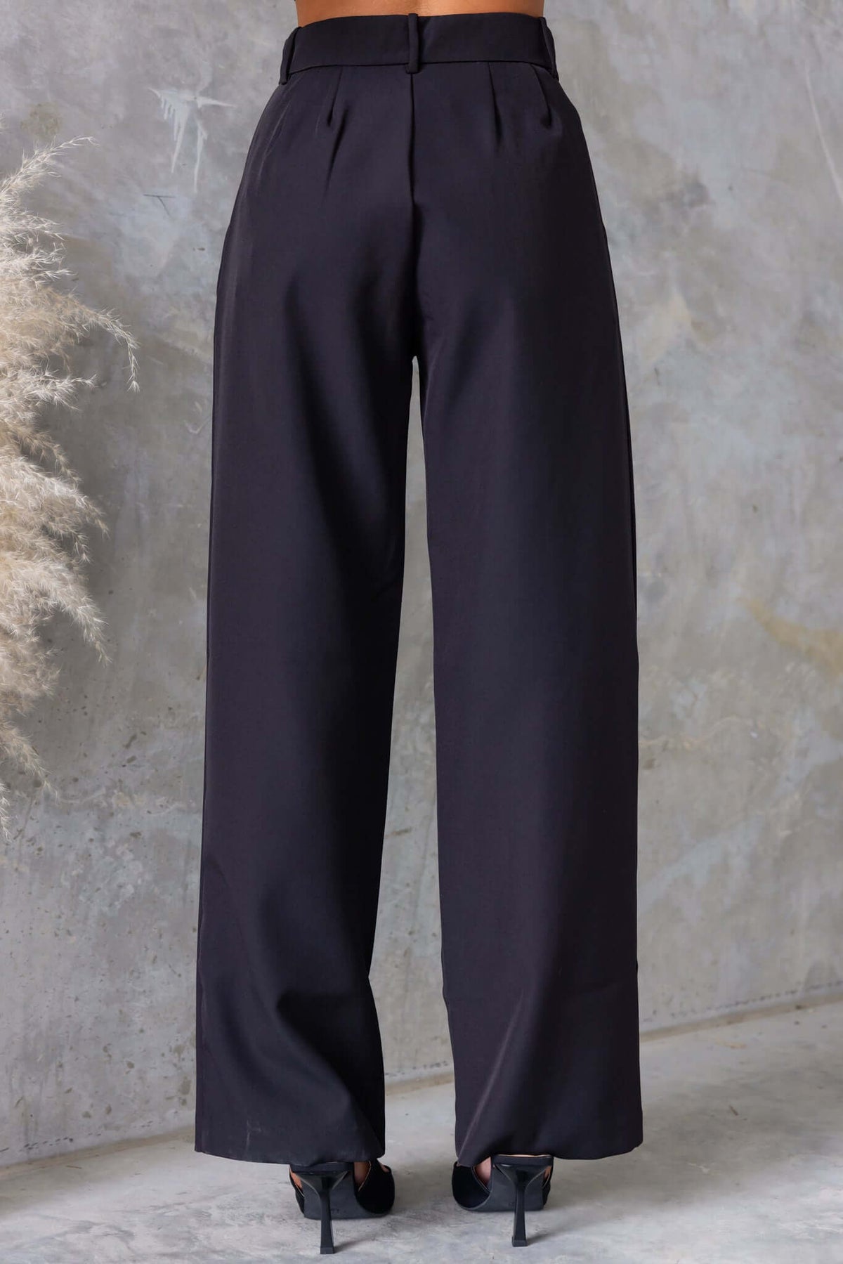 Back view of Gette Pants, mid-high waist fit, wide-leg style, featuring pockets and made from 100% polyester.