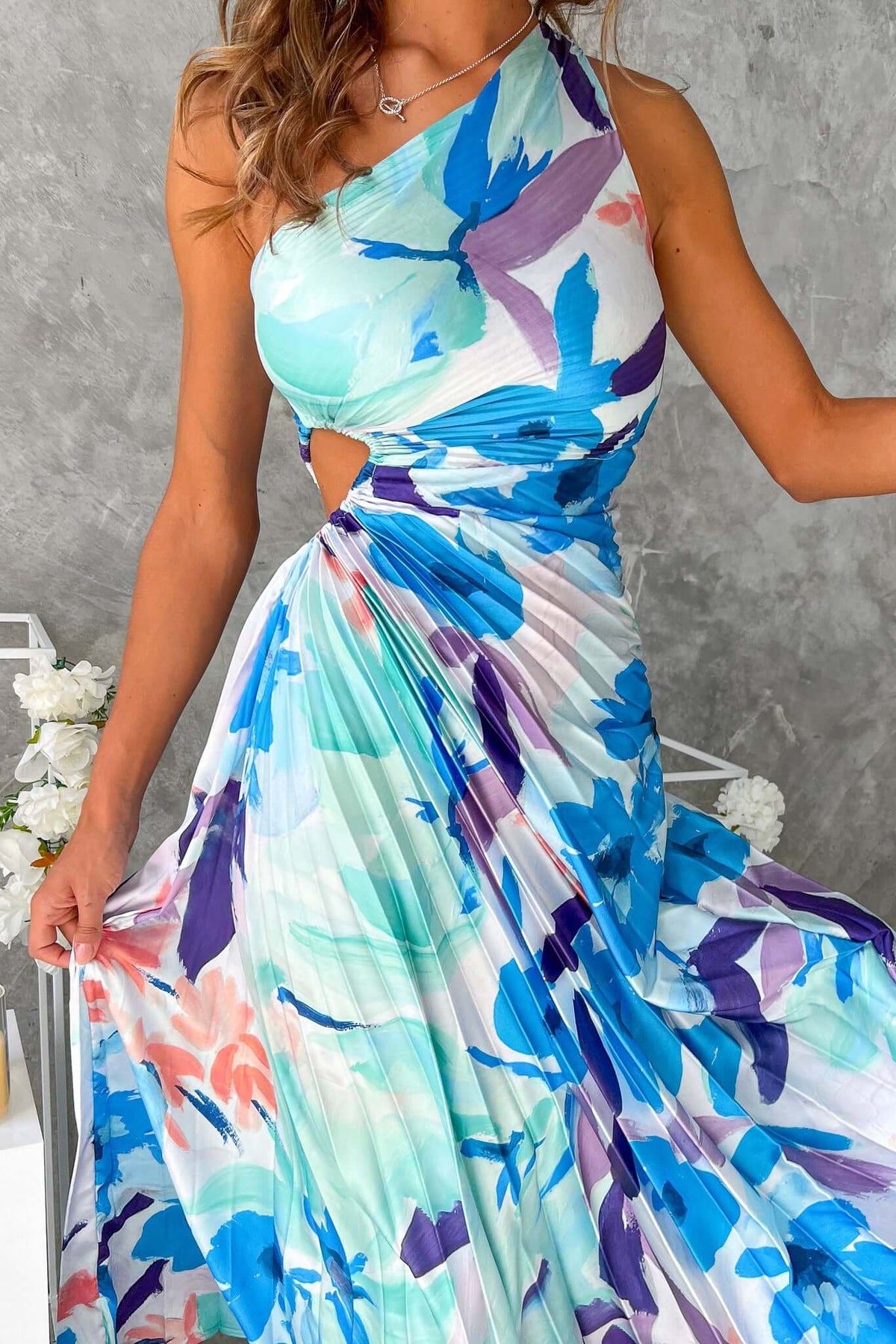 Model wearing an elegant one-shoulder Olympia maxi dress with a floral print and cut-out waist detail.