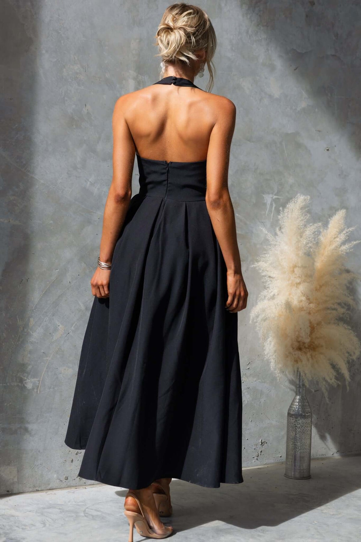 Back view of a woman wearing a stylish black Jhene Maxi Dress, featuring elegant design and flowing silhouette.