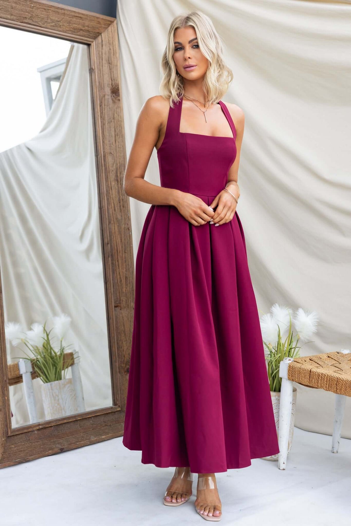 Jhene Maxi Dress in burgundy, featuring a square neck, halter straps, and a flowy, lined design, displayed in a stylish setting.