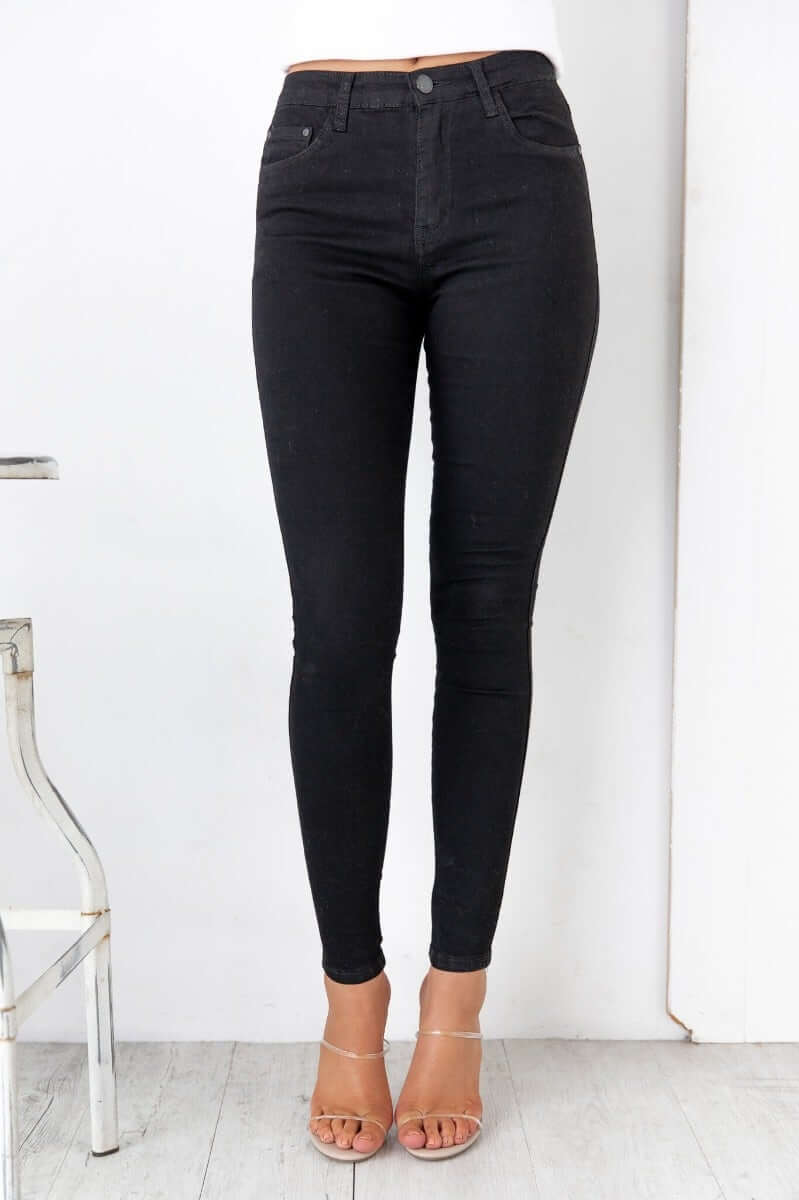 Justified Jeans in black, mid-high waist, skinny fit, featuring pockets and firm stretch material.