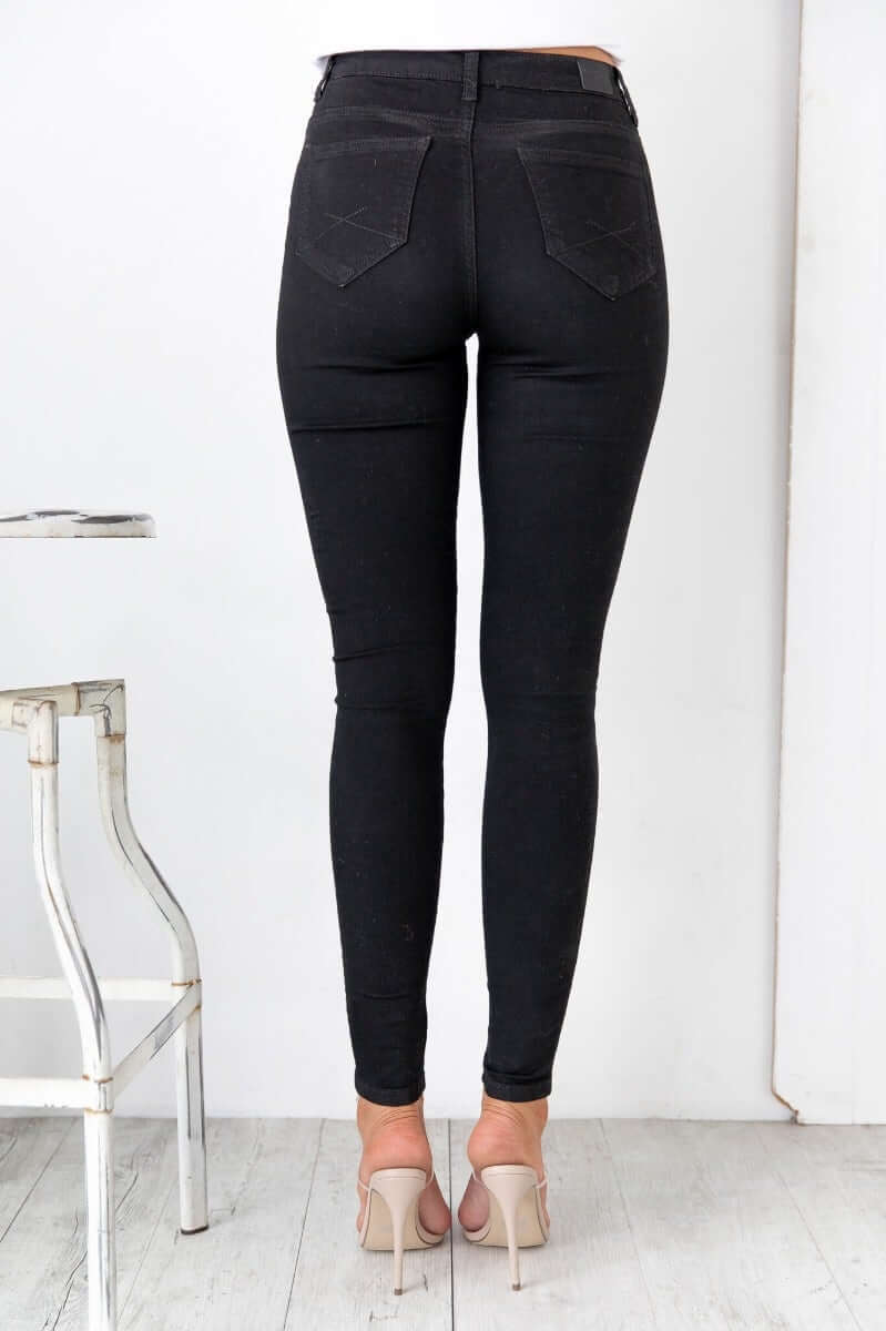 Justified black jeans with mid-high waist, firm stretch, and pockets, shown from the back.