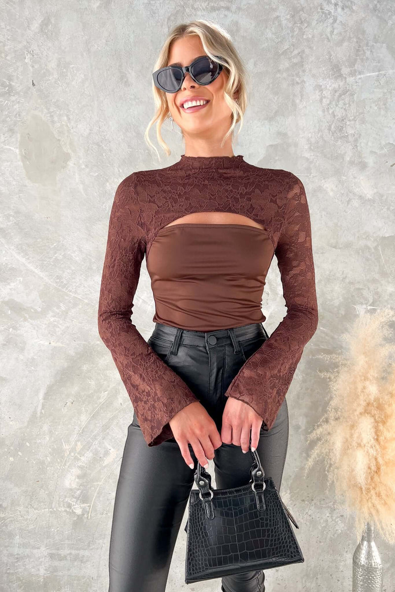 Fashionable Kaiya Top featuring mock neckline, cut-out bust, lace panel, worn with stylish sunglasses and pants.