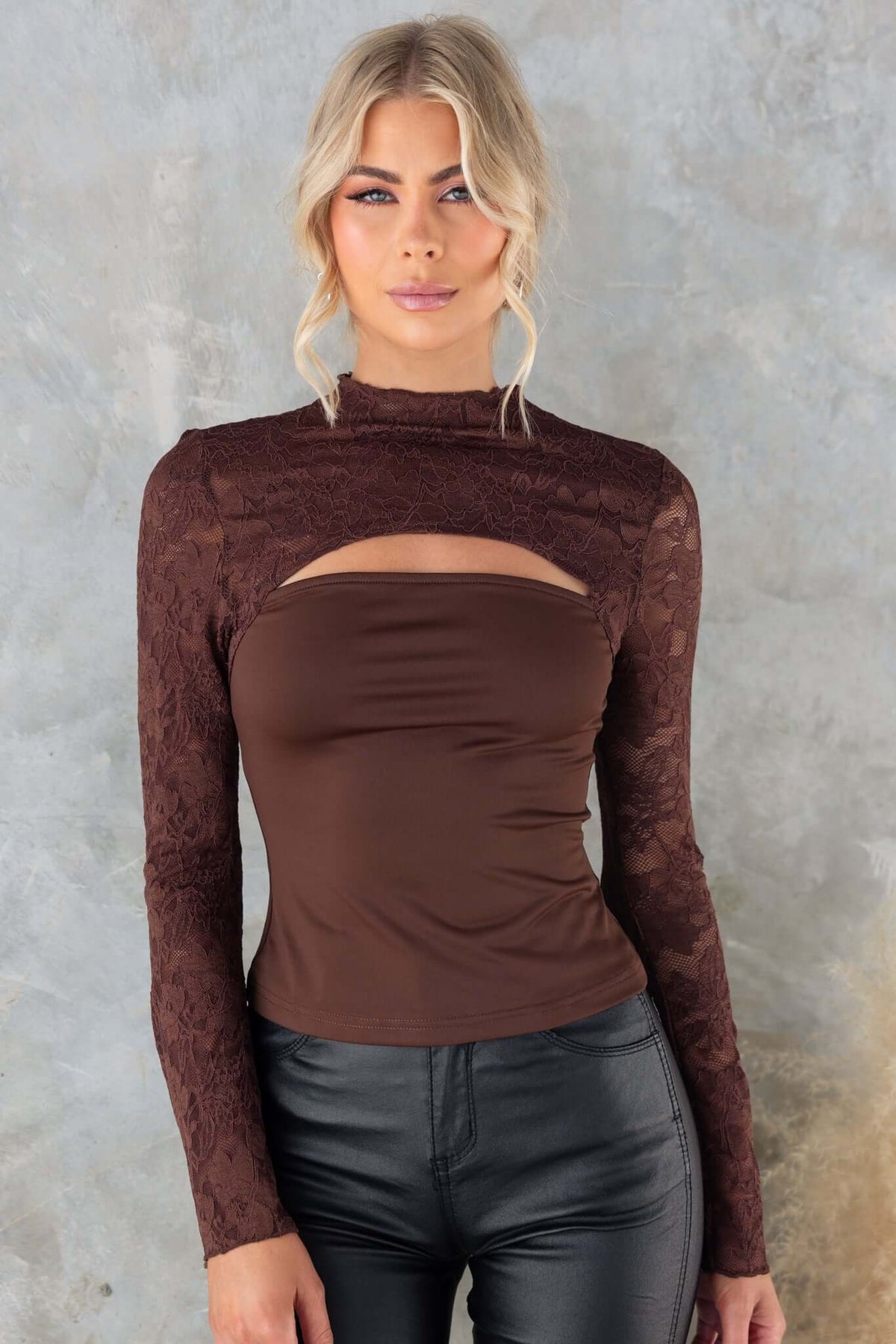 Brown mock neck Kaiya Top with cut-out at bust and lace panel, styled with black pants.