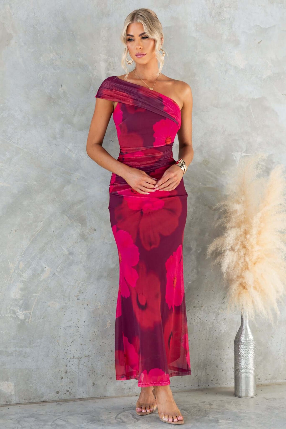 Model wearing a Korren Maxi Dress, one-shoulder neckline, featuring floral mesh fabric in vibrant pink and red.