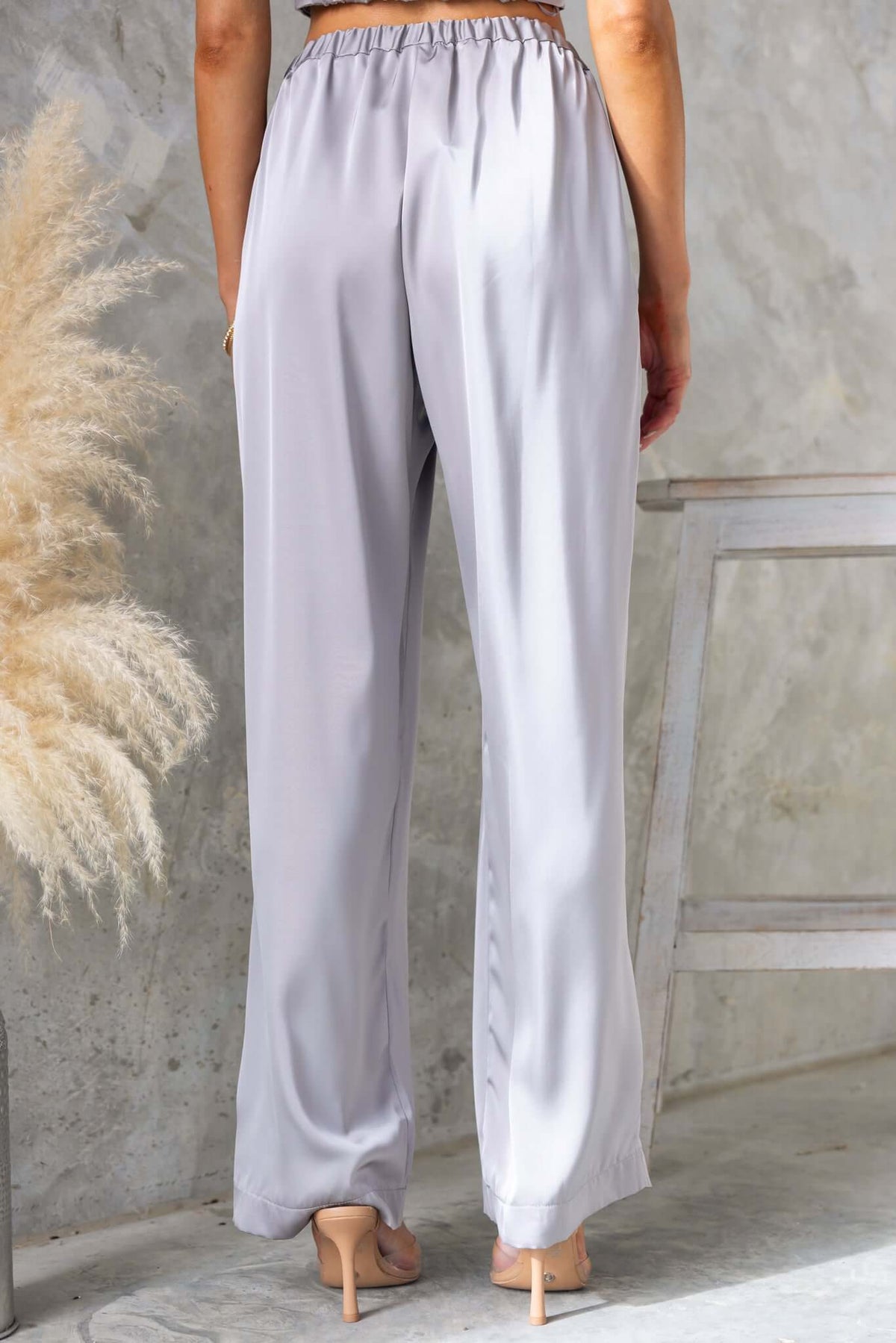 Back view of Kortez Pants in light gray satin, featuring a mid-high waist, elastic waistband, and loose fit.