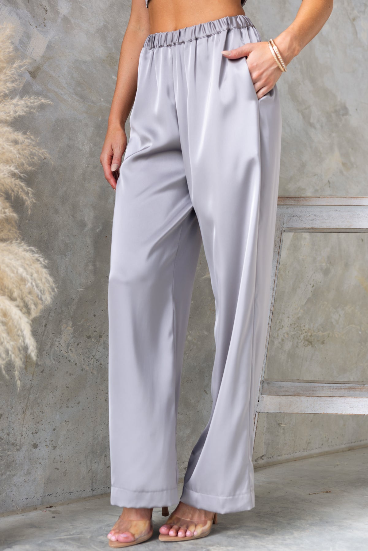 Stylish Kortez Pants in light grey satin, featuring a mid-high waist, elastic waistband, and pockets.