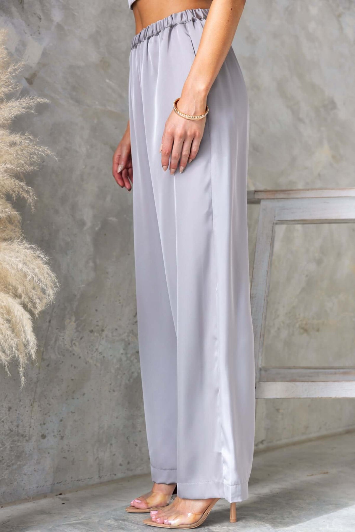 Side view of Kortez Pants in satin, featuring mid-high waist fit, elastic waistband, and pockets.