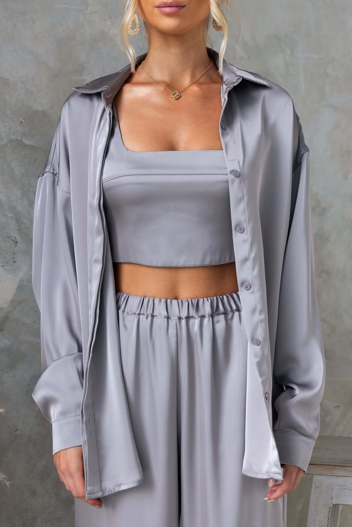 Model wearing Kortez shirt in satin material, featuring a collar and button-up front, styled with matching grey outfit.