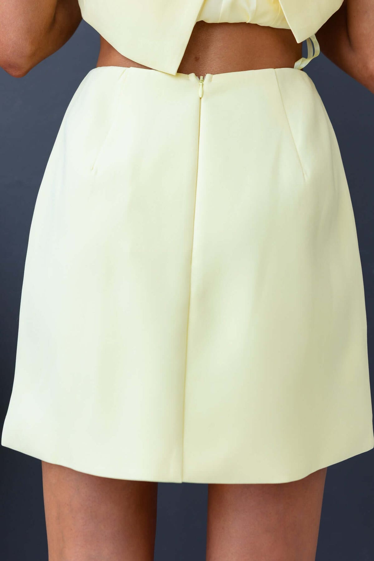 Back view of a Laredo skirt in pastel yellow with a mid-high waist, invisible zip closure, and lined design.