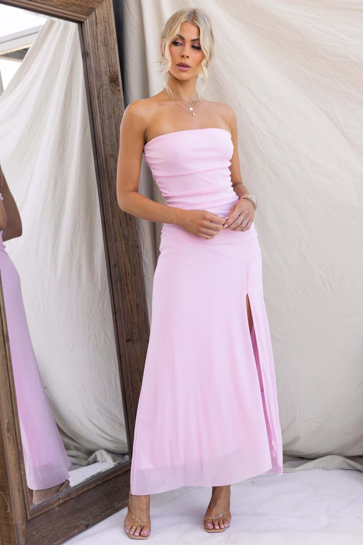 Model wearing Legrand Maxi Dress, a strapless pink dress with a front split, showcasing a stylish and elegant look.