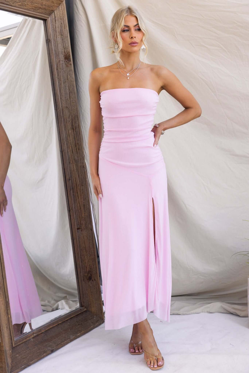 Strapless Legrand Maxi Dress in pink with front split, styled elegantly in front of a mirror.