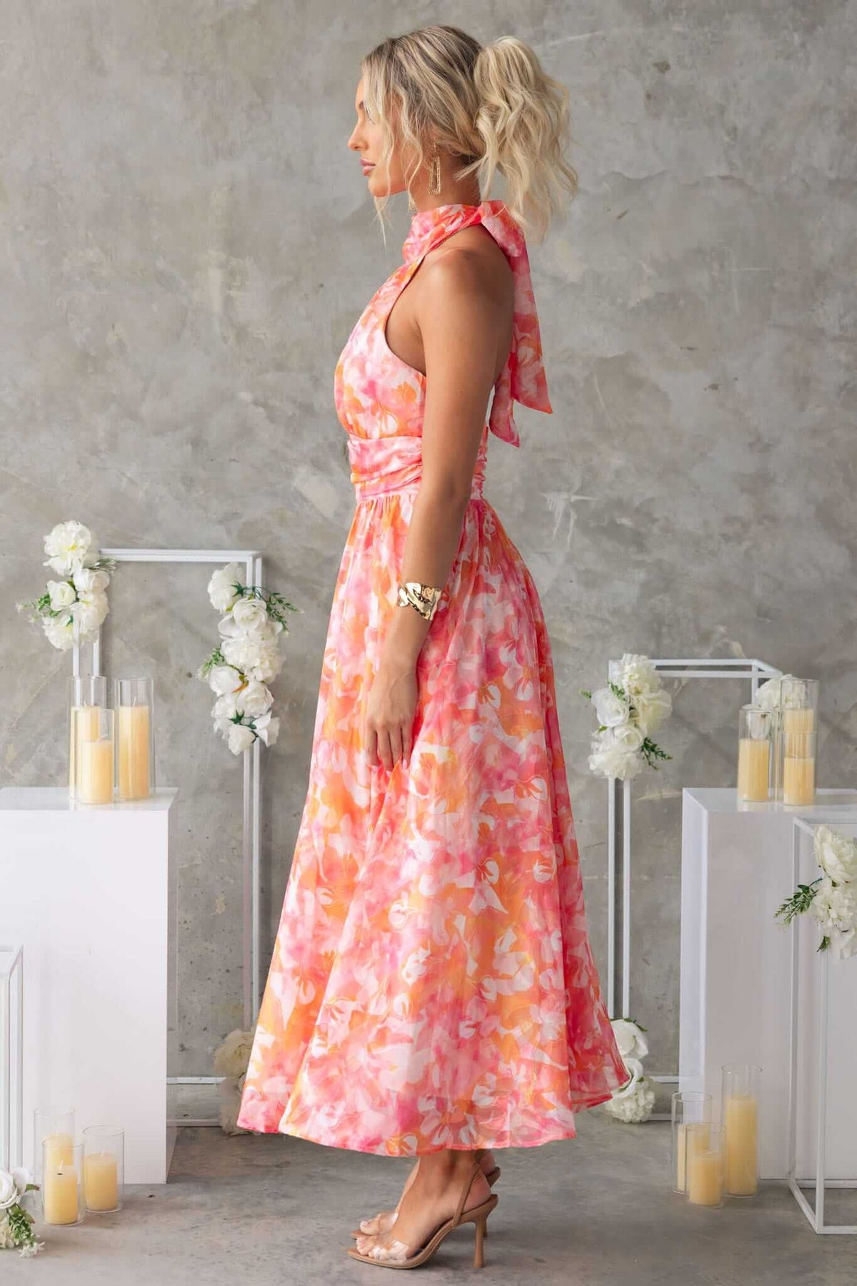Side view of a woman in a vibrant floral little things maxi dress with high tie neckline and flowing skirt.