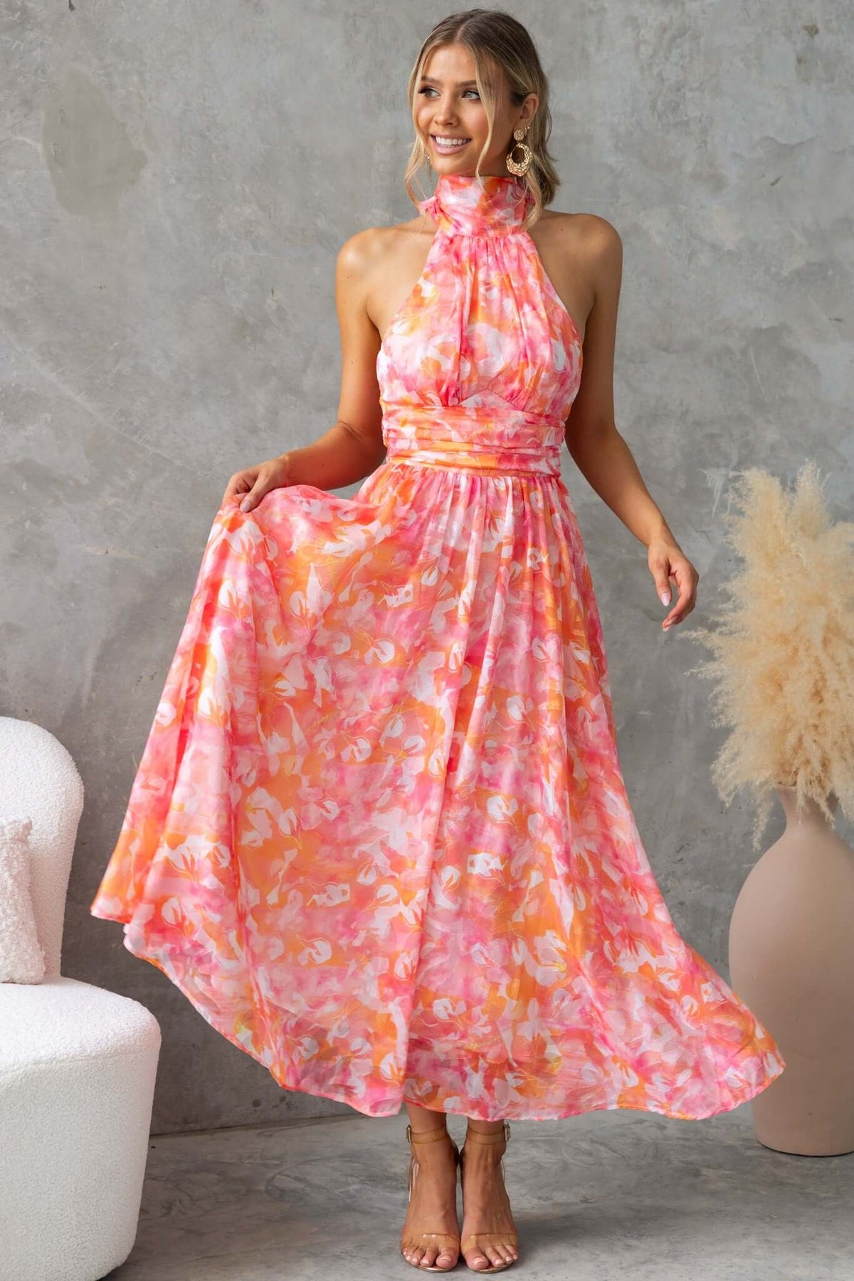 Woman wearing a pink floral Little Things Maxi Dress with high tie neckline, showcasing a flowing design.